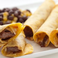 Steak and pepperjack taquitos on white plate.