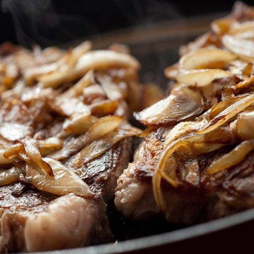 Steak with bourbon onions in skillet.