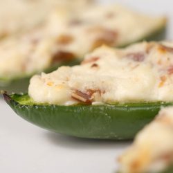 Cream cheese and bacon stuffed jalapenos on white plate.