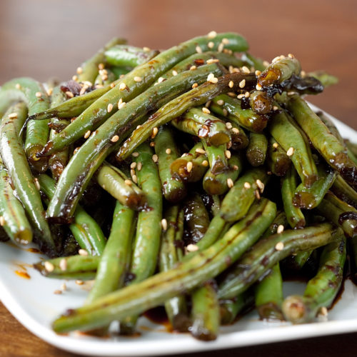 Szechuan green beans on white plate.