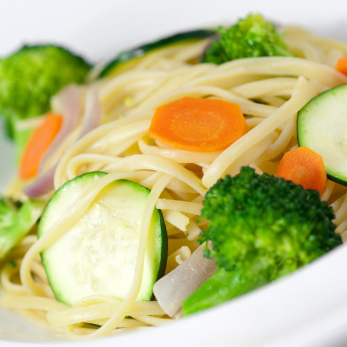 close up of vegetable linguine in white bowl.