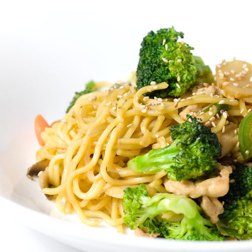 Yakisoba with chicken and veggies in white bowl.