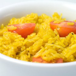yellow rice with cherry tomatoes in white bowl.