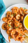 Overhead photo of air fryer fried shrimp on white plate with blue napkin.