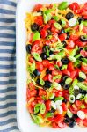 Overhead photo of seven layer dip in a white dish with striped towel.