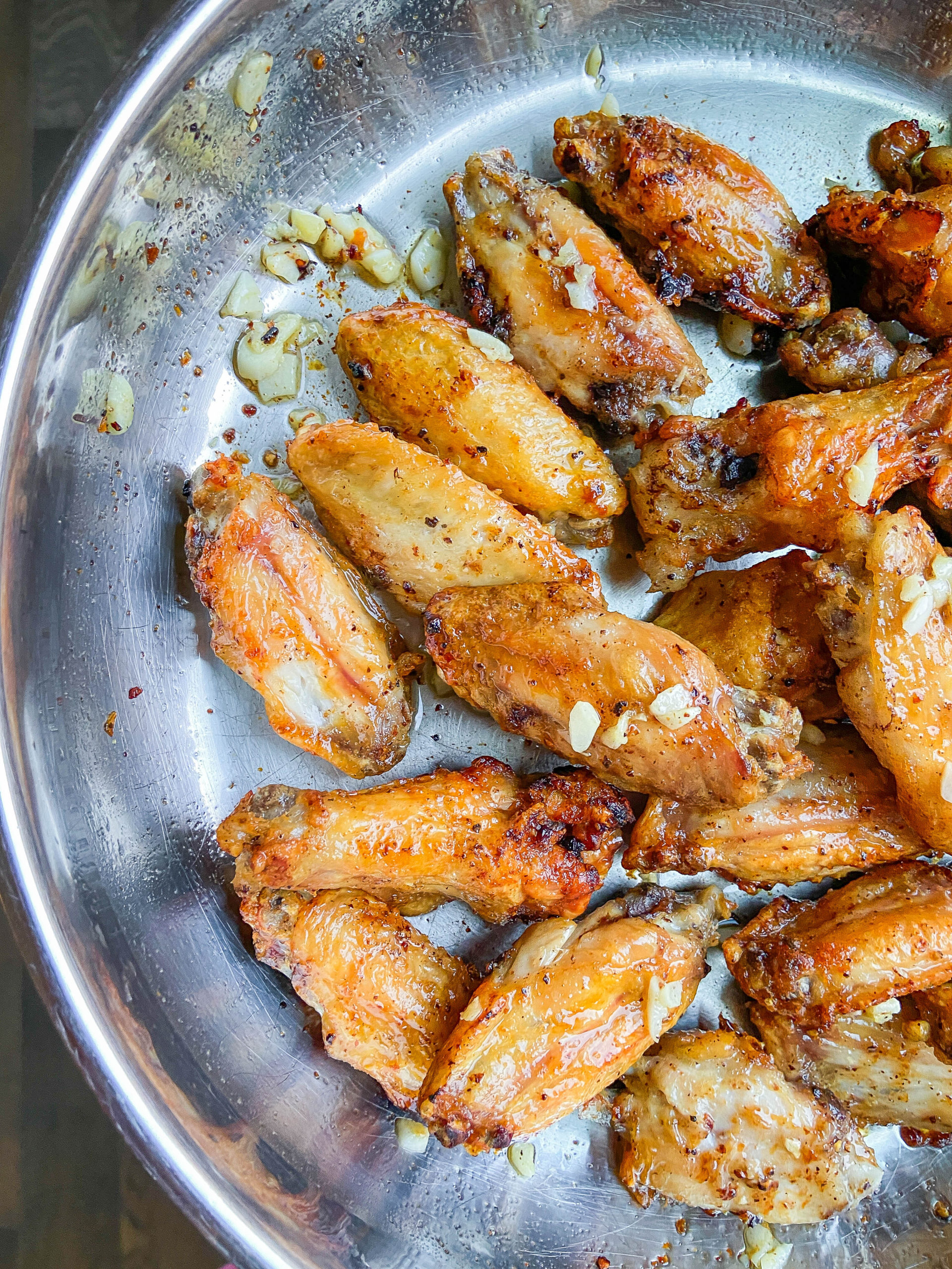 Cooked garlic wings in a frying pan. 