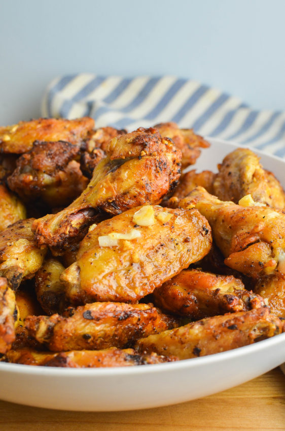 Side angle photo of garlic chicken wings in a white bowl.