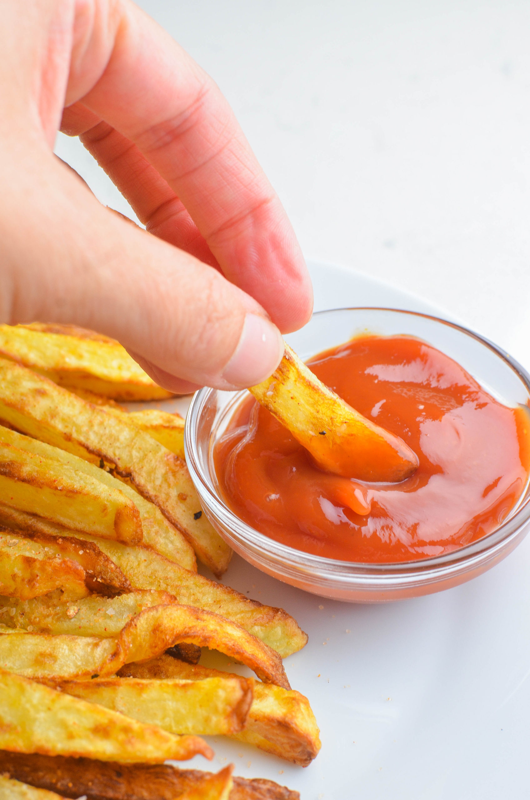 Dipping air fried french fries in ketchup