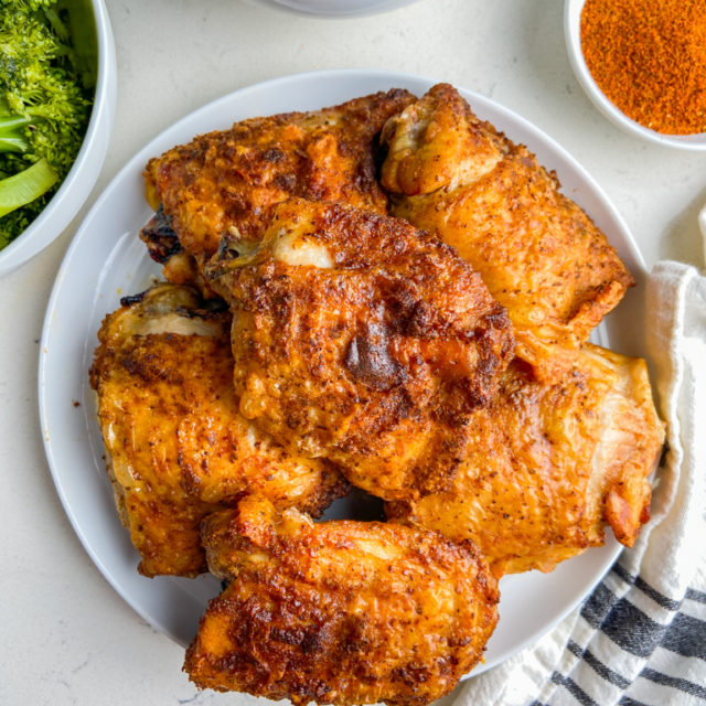 Overhead photo of air fryer chicken thighs on white plate with broccoli and mashed potatoes.