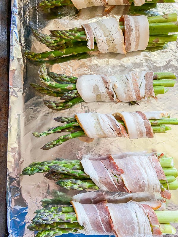 Bacon wrapped asparagus on aluminum foil lined baking sheet. 