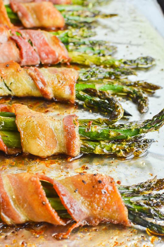 Asparagus wrapped in bacon on aluminum foil. Side angle shot. 