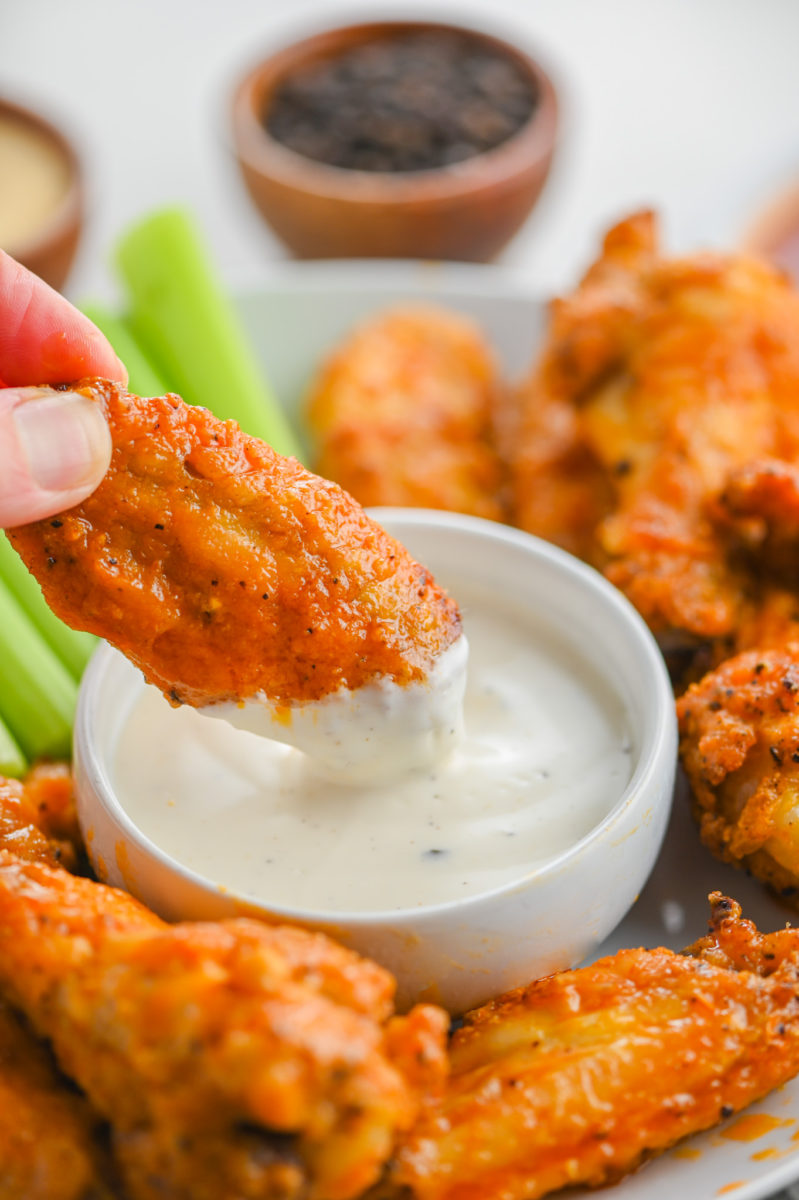 Hand holding chicken wings.