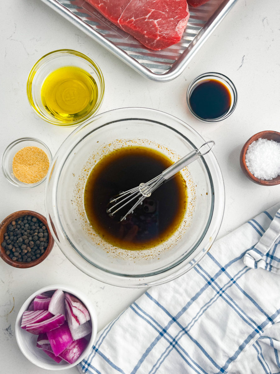 Balsamic marinade in a clear glass bowl with a whisk.