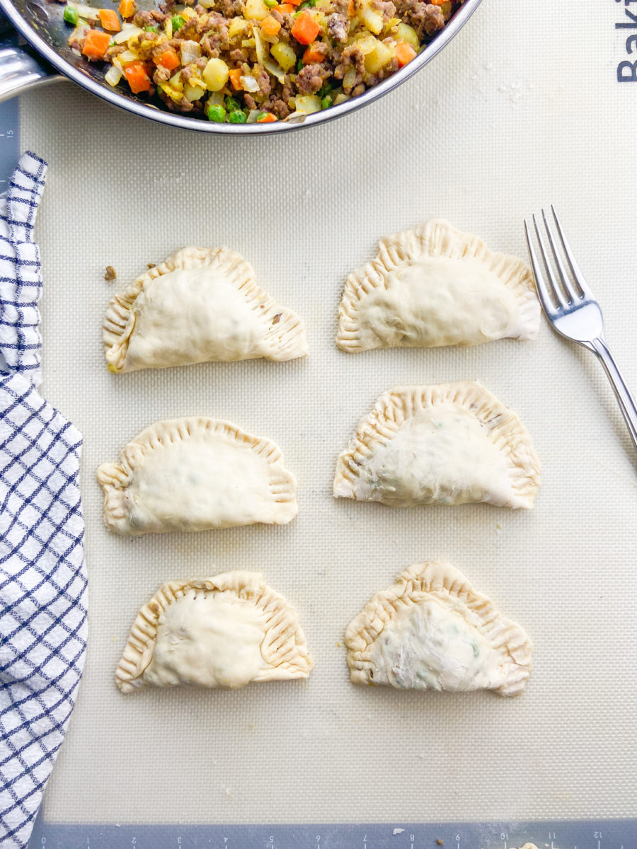 uncooked beef samosas on cutting surface. 