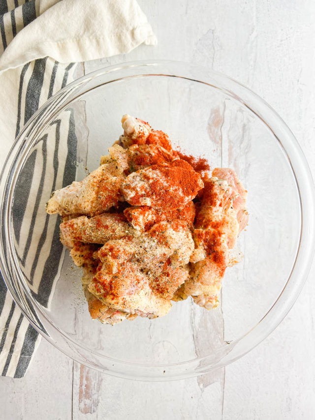 Overhead photo of raw chicken wings with seasonings. 