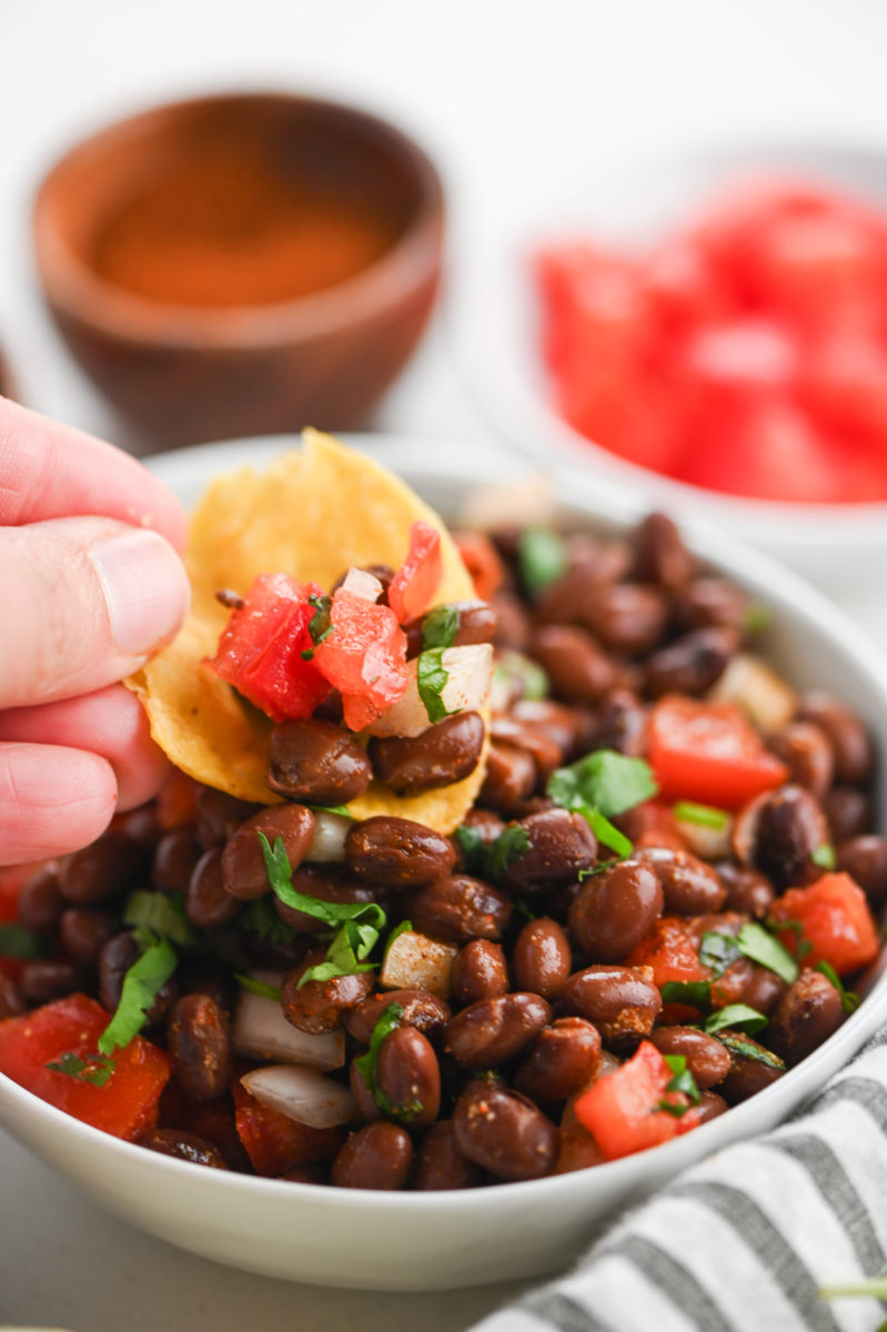 A chip dipping in black bean salsa. 