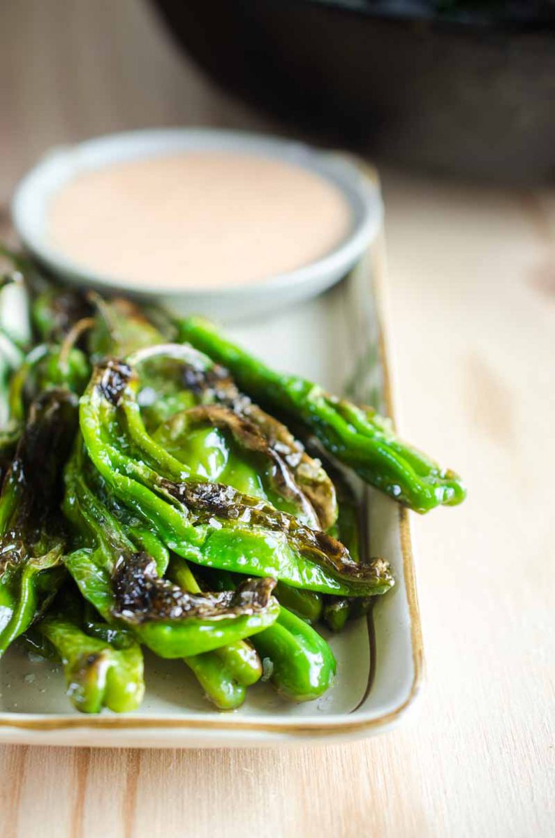 Blistered shishito peppers are pan fried until crispy and served with a sriracha cream sauce. A quick and easy appetizer for pepper lovers