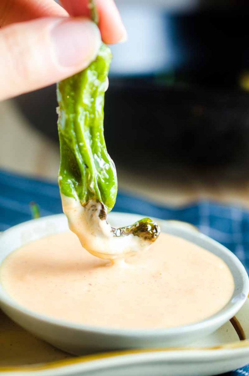 Blistered shishito peppers are pan fried until crispy and served with a sriracha cream sauce. A quick and easy appetizer for pepper lovers! 