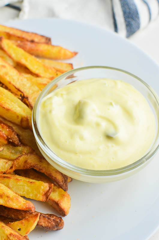 Burger spread in a clear bowl with french fries on a white plate. 