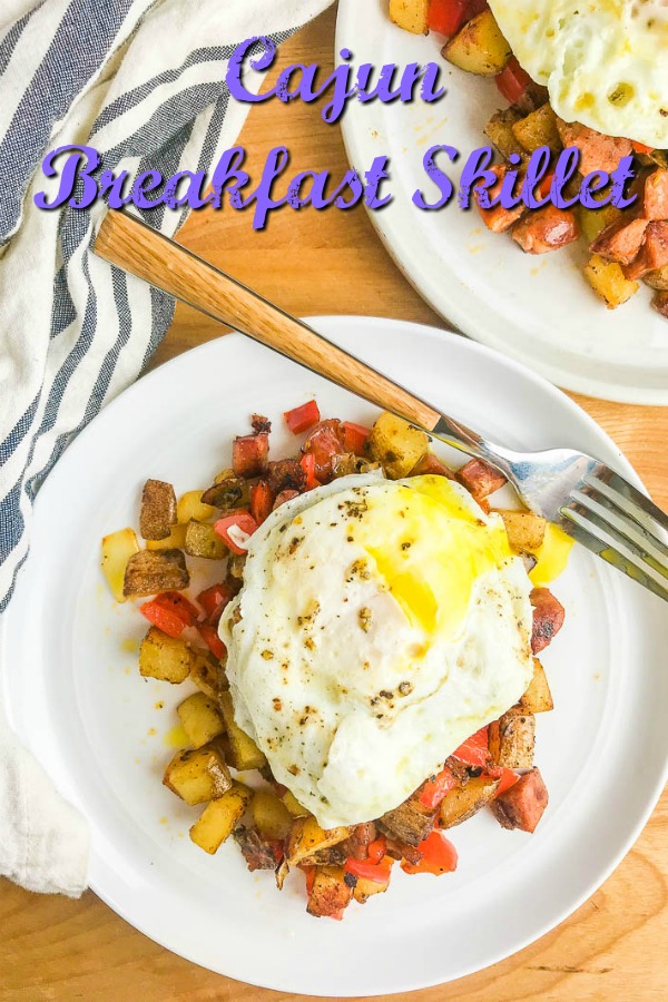 Cajun Breakfast Skillet is loaded with potatoes, andouille sausage, onions, bell peppers and cajun seasoning. Then topped with a perfectly fried egg. It's an easy, hearty way to start your day!  #breakfast #cajun #andouillesausage #eggs #brunch 