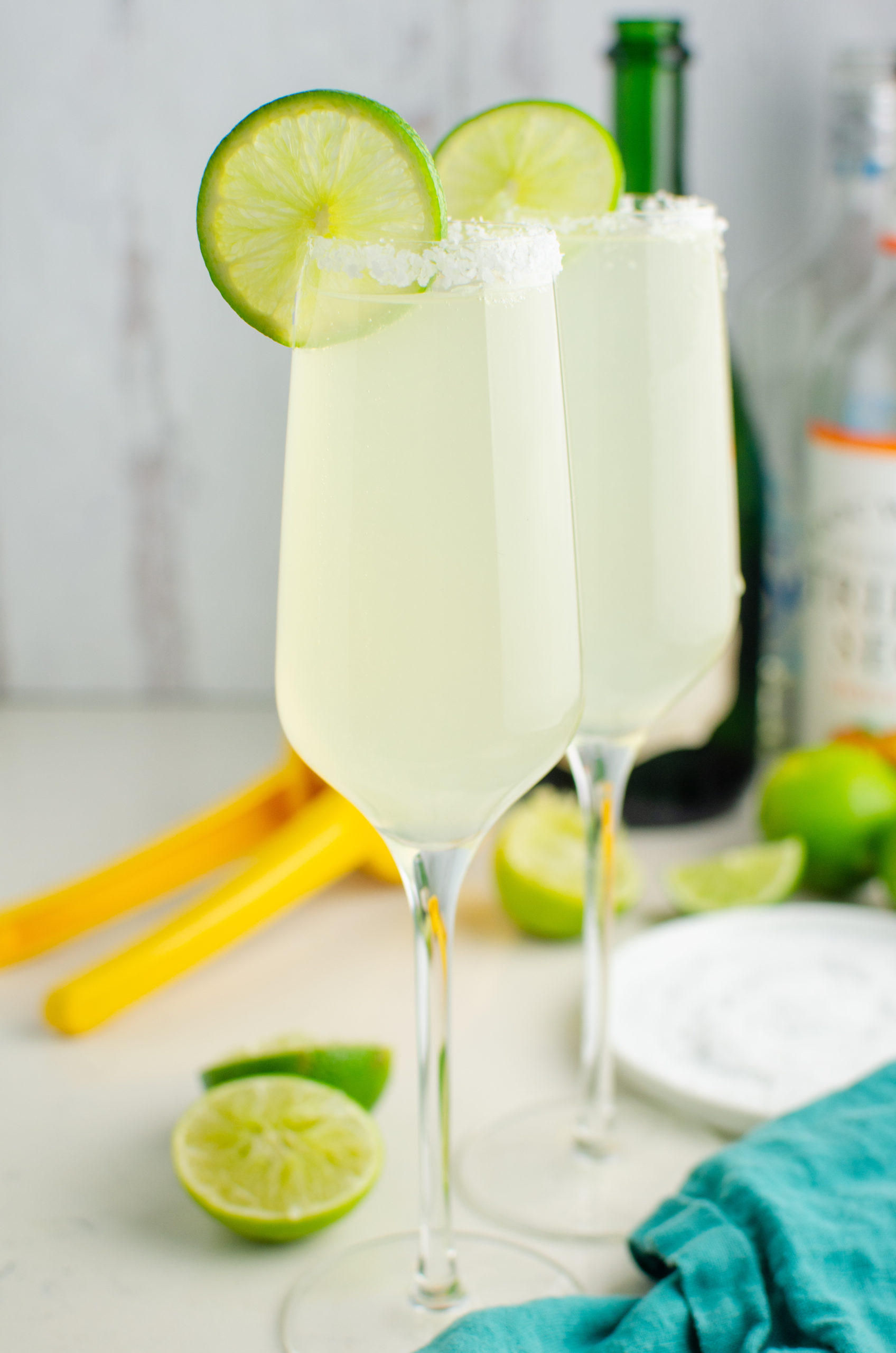 Two champagne margaritas garnished with lime. 