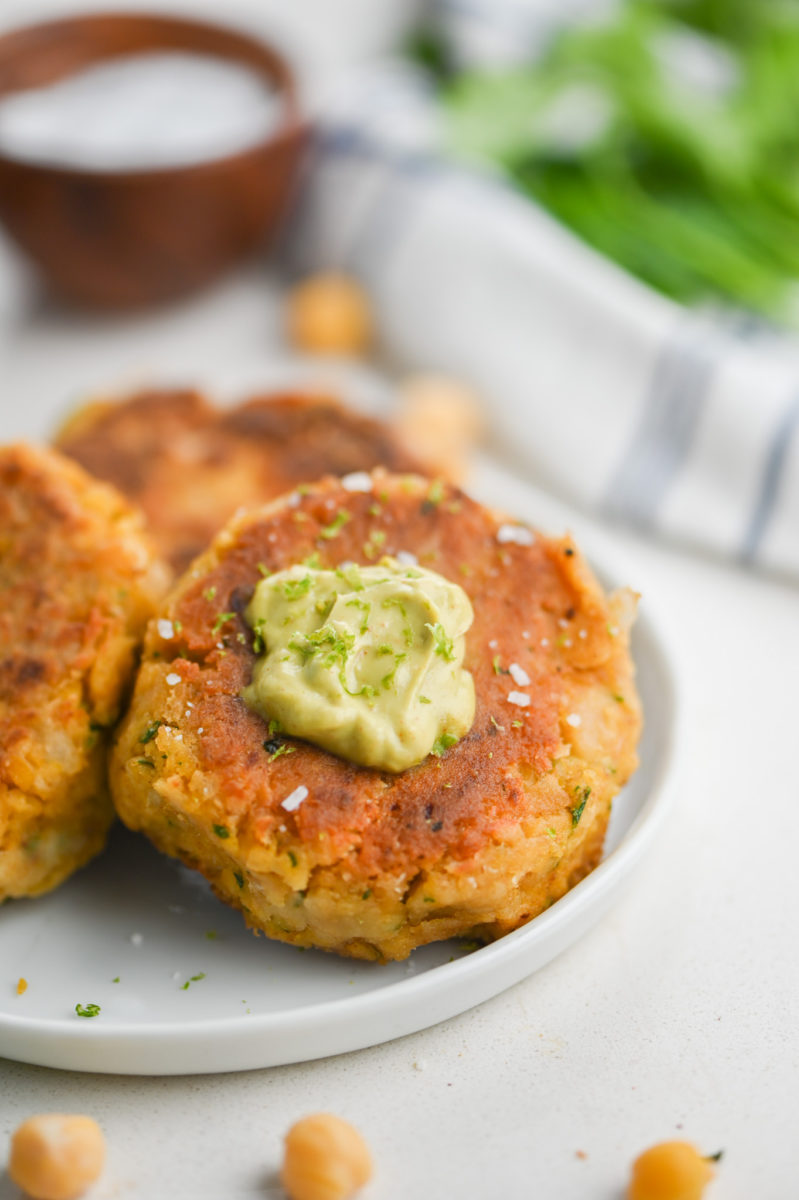 Chickpea patty with avocado sauce on white plate. 