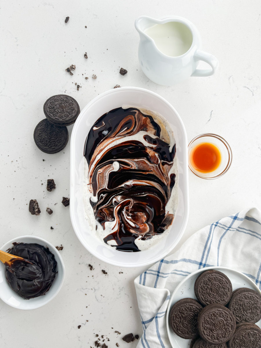 Half of ice cream in white container with a swirl of hot fudge. 