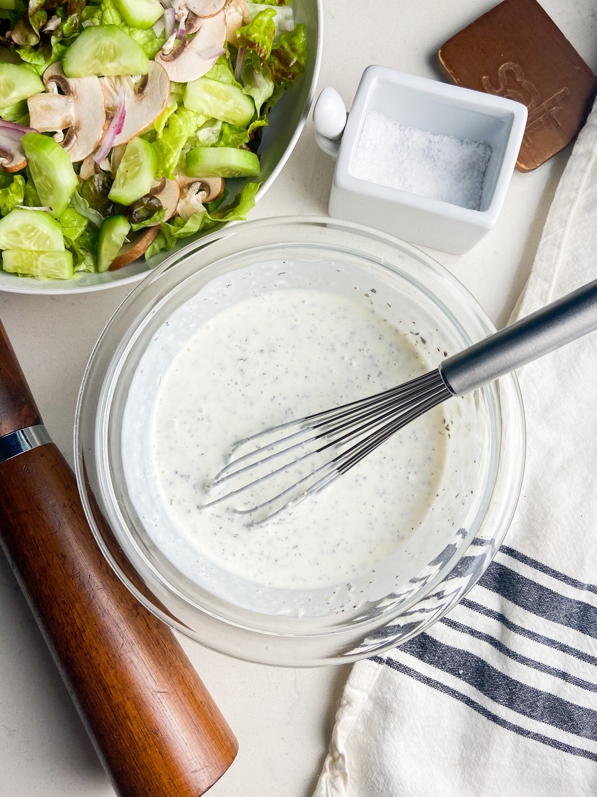 Overhead photo of salad dressing in a bowl with a wire whisk.