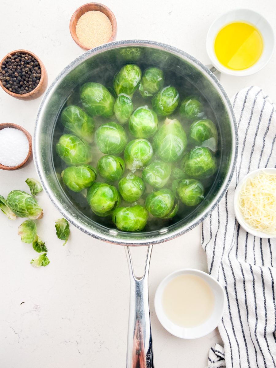 Boiling brussels sprouts in a pot of water with a white background. 