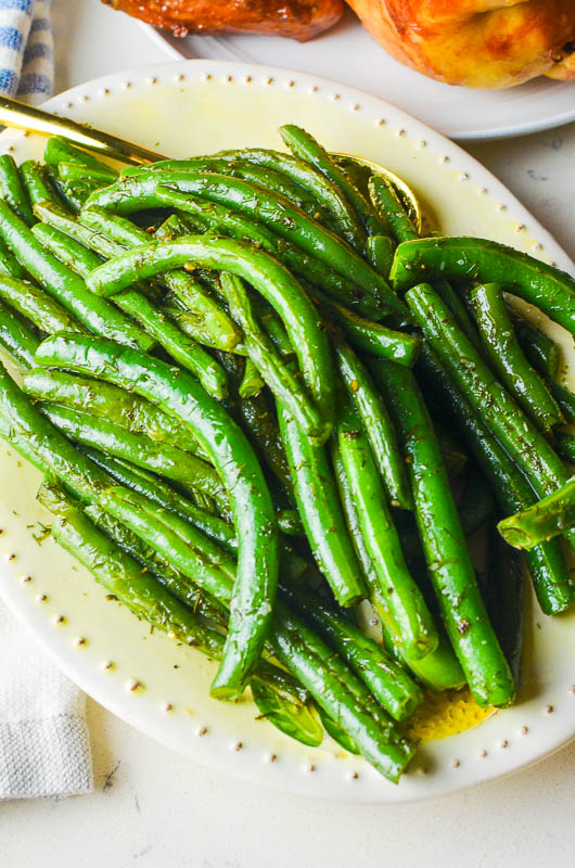 Dill green beans on a white oval dish. 