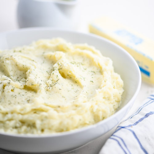 dill mashed potatoes in white bowl.