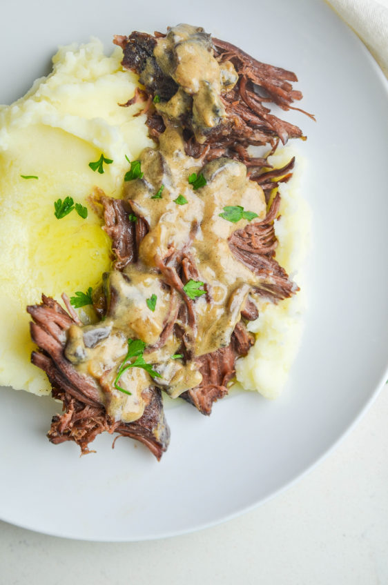 overhead photo of dutvh oven pot roast with mushroom gravy on white plate.