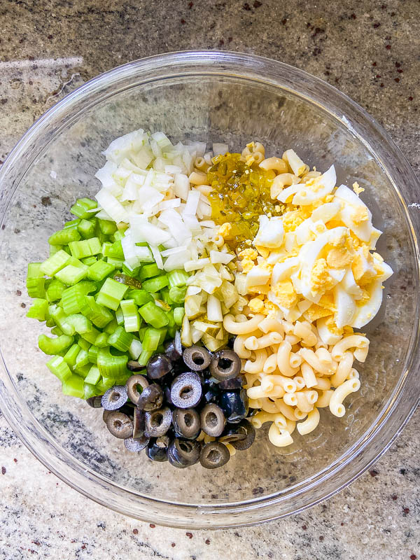 Ingredients for macaroni salad in a glass bowl. 