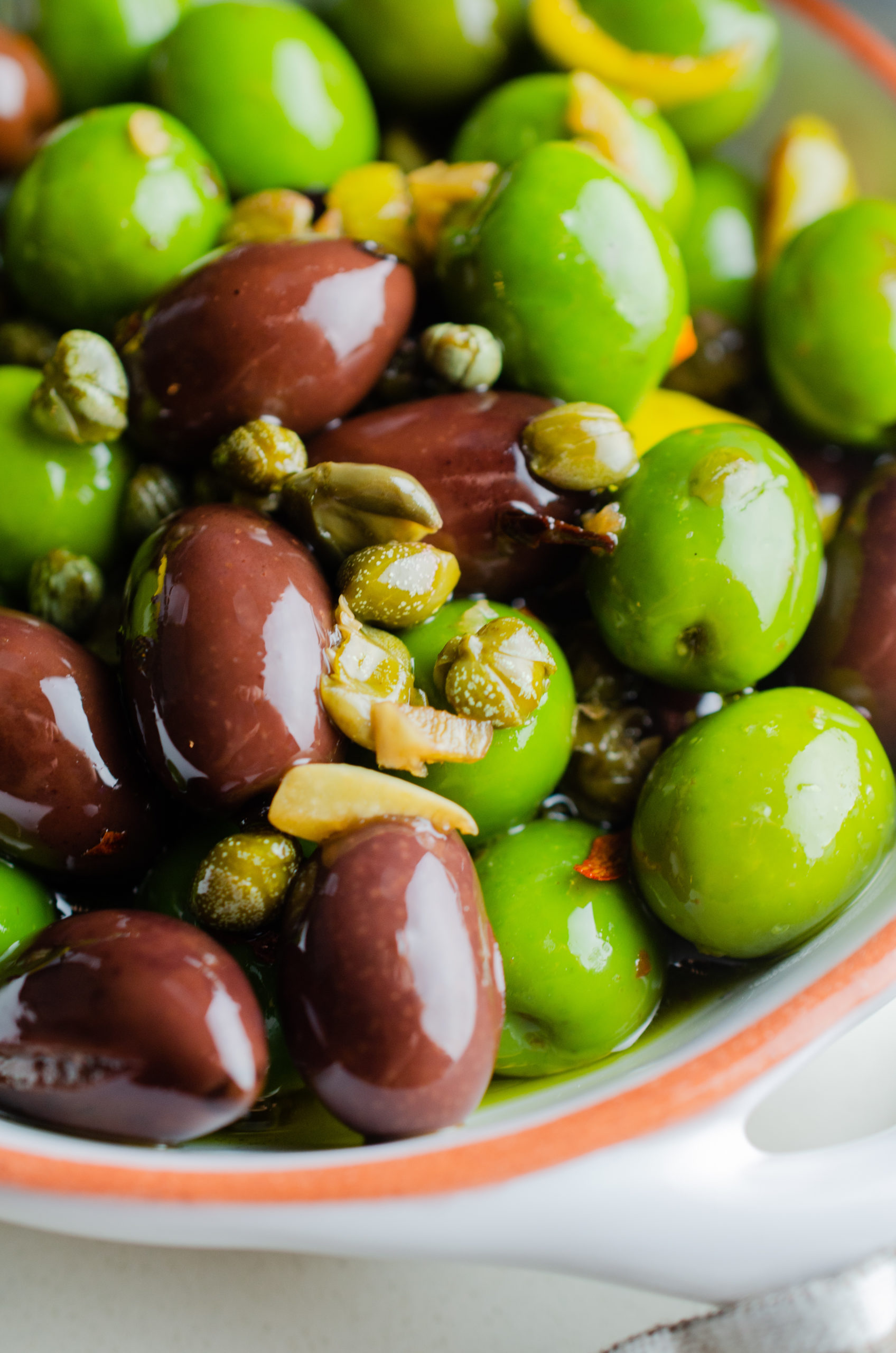 Side angle photo of marinated olives in a white dish. 