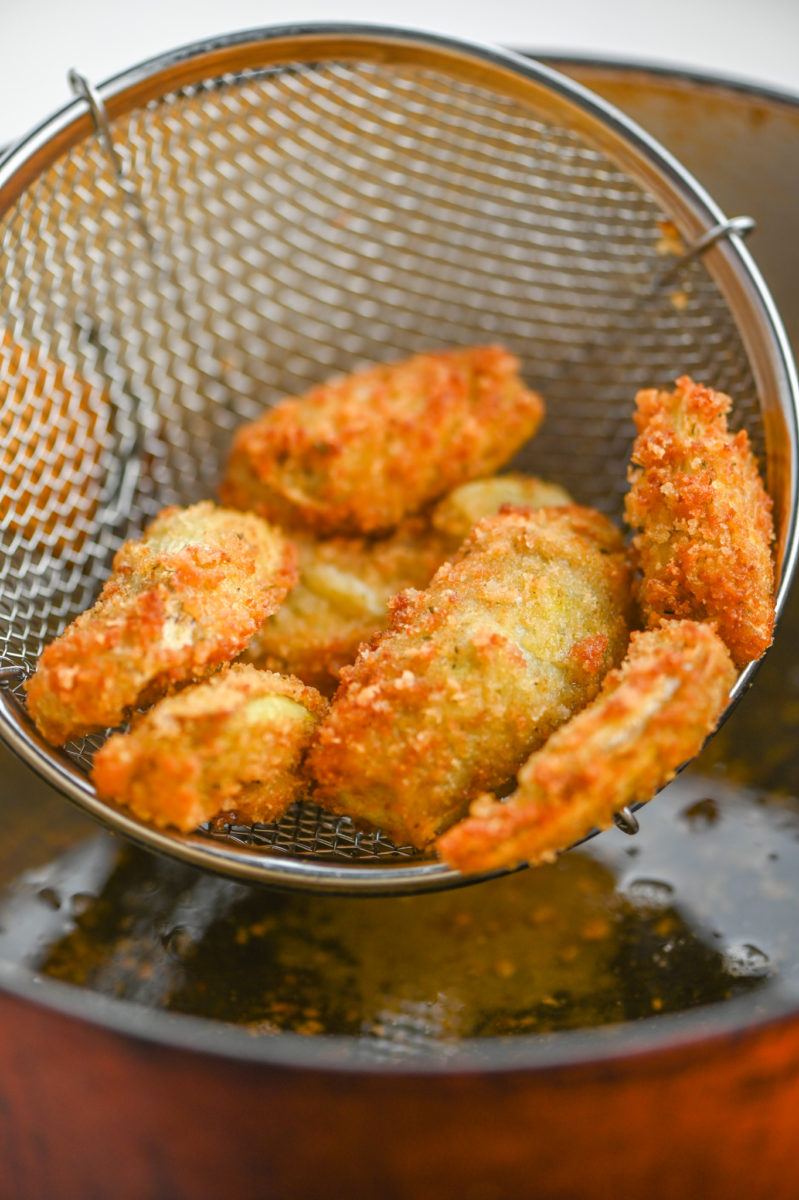 Fried Artichoke Hearts in strainer over oil. 