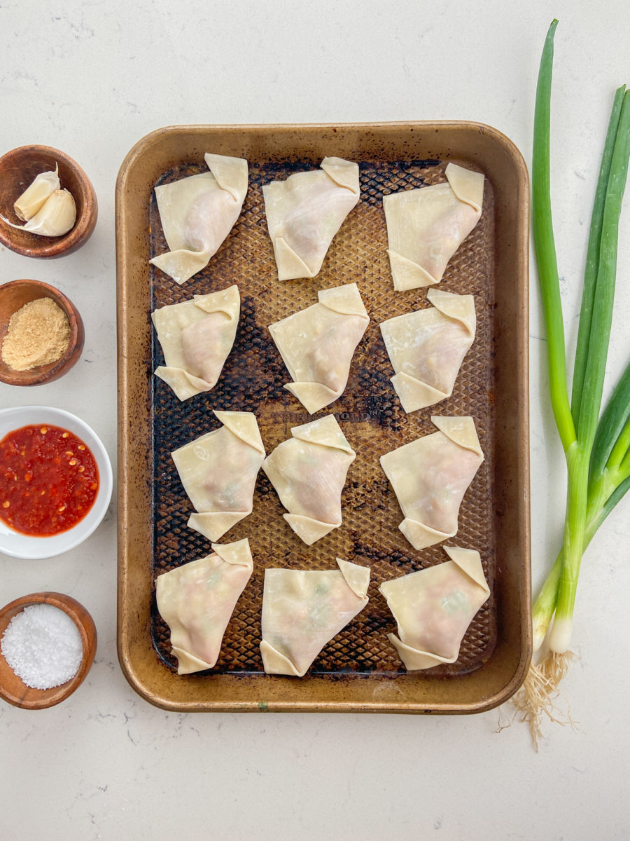 Pork wontons on baking sheet for freezing. 