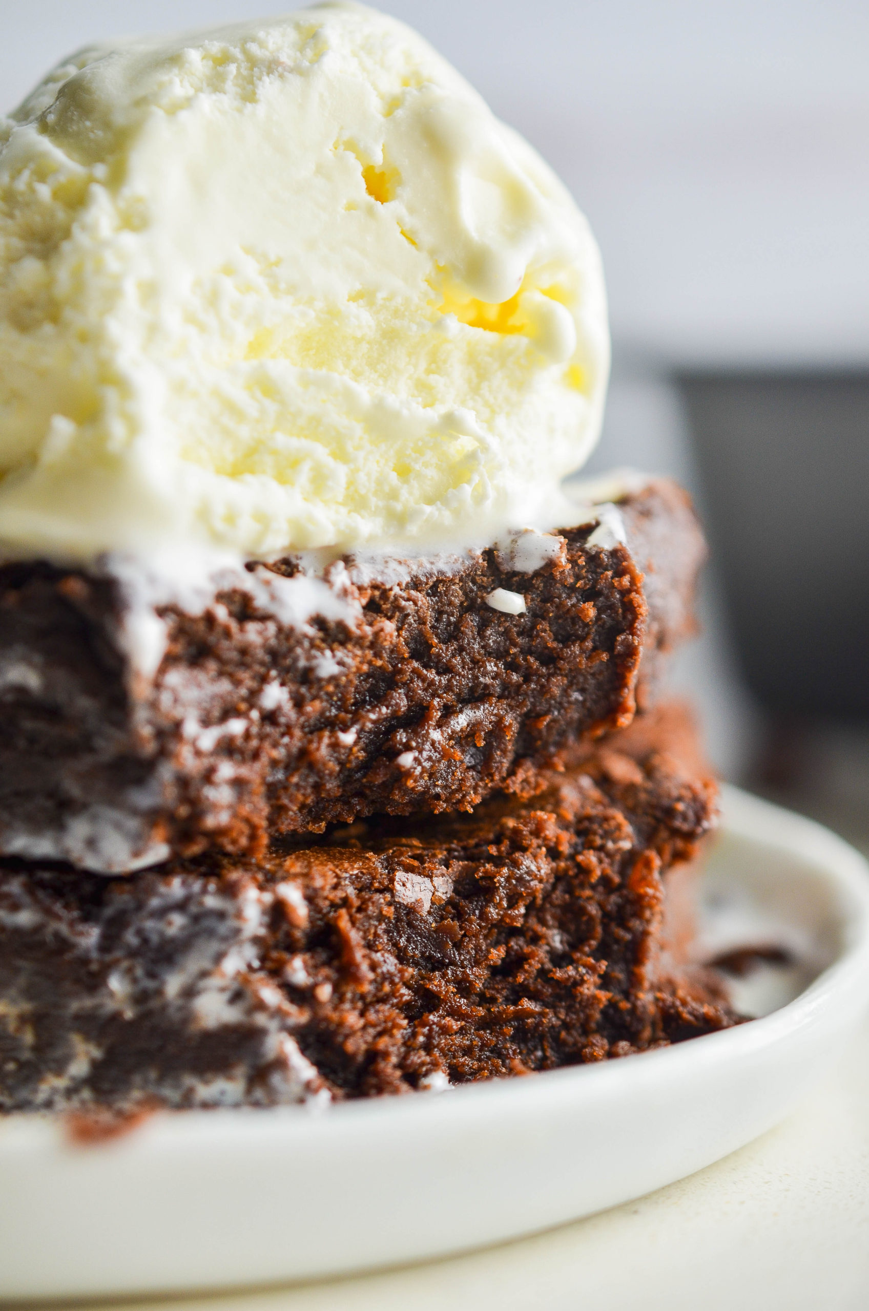 Side angle photo of brownies with ice cream on top. 