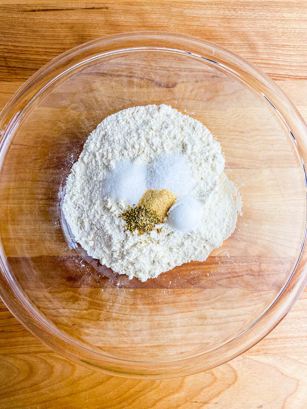 Dry ingredients in a clear bowl on a cutting board.