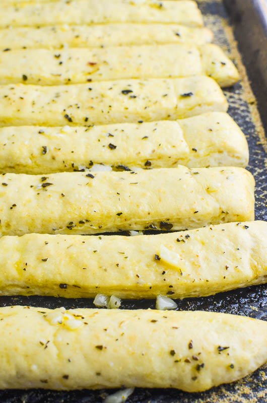 Side shot of garlic breadsticks on a sheet pan.