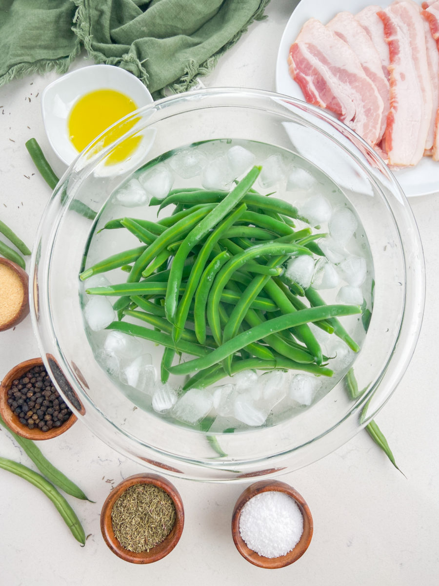 Blanched green beans in bowl of ice water. 