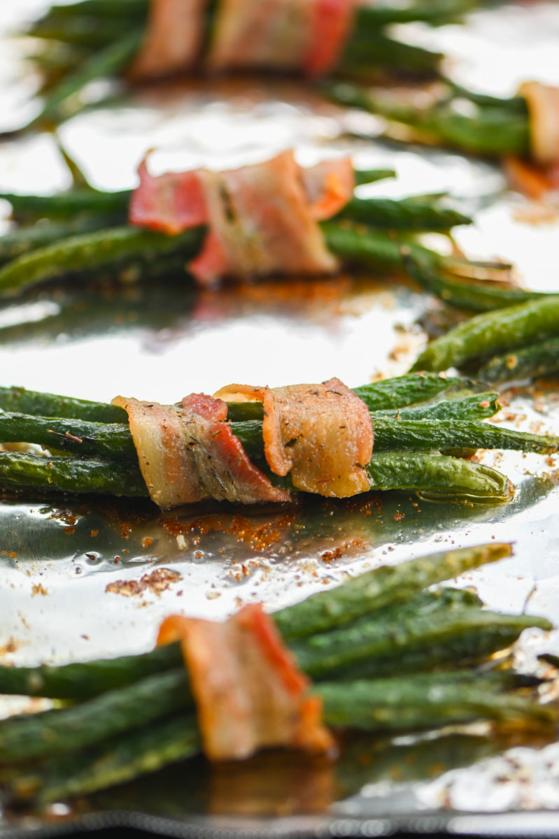 Cooked green bean bundles on baking sheet. 