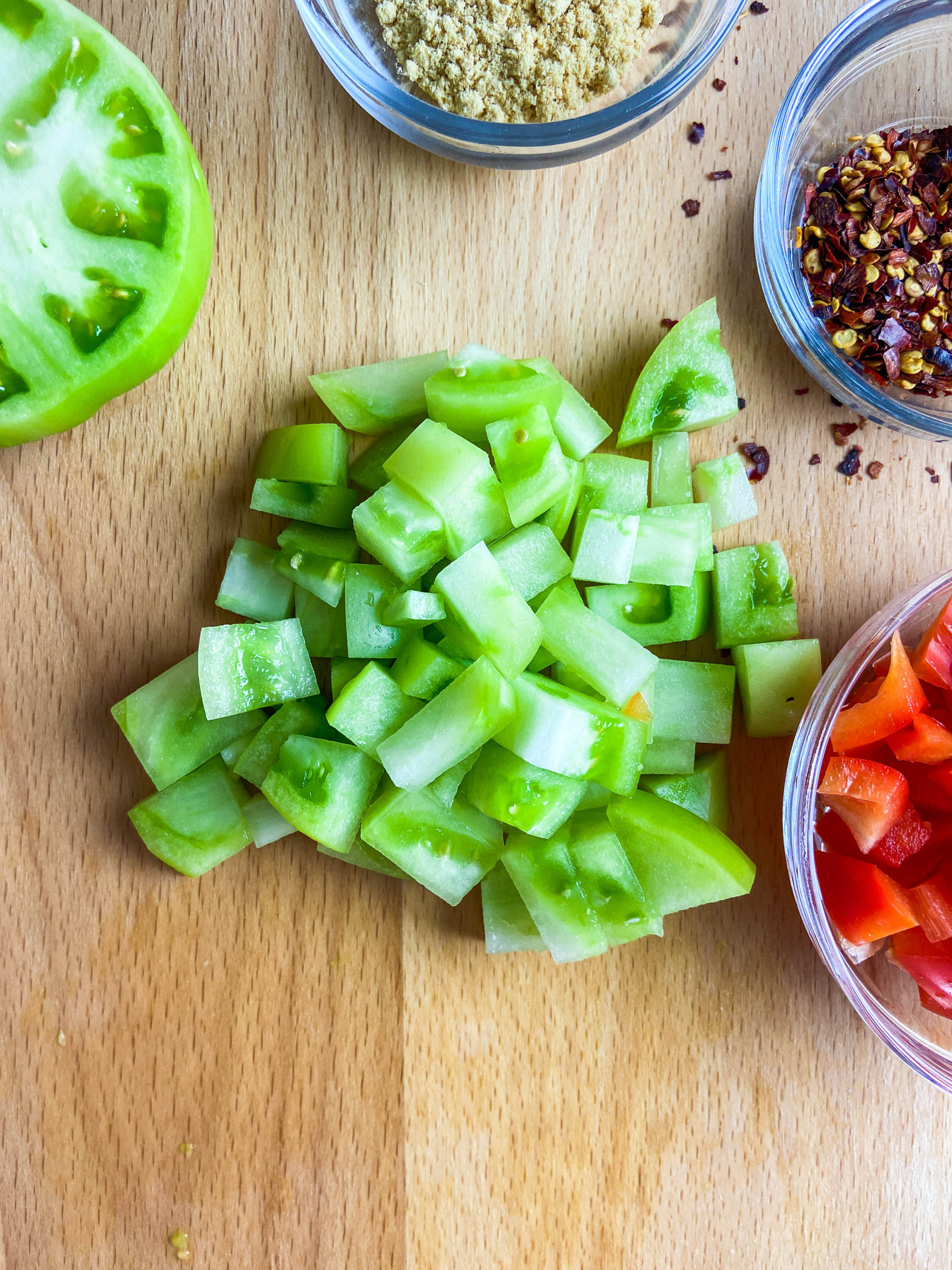 Diced green tomatoes on a wooden cutting board.