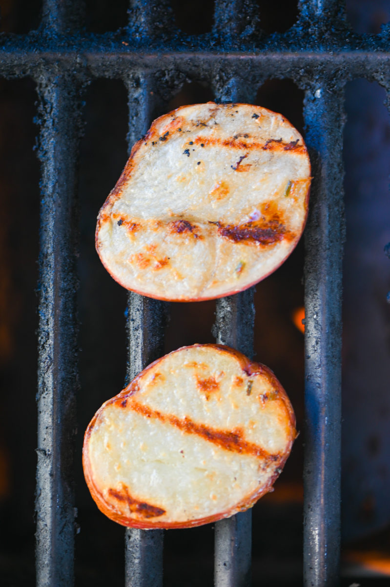 Sliced red potatoes on grill. 
