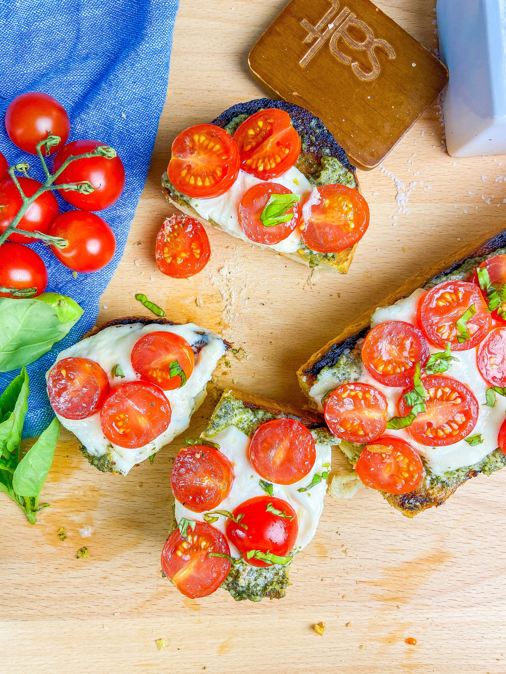 Overhead photo of slices of caprese cheese bread on a wooden cutting board. 