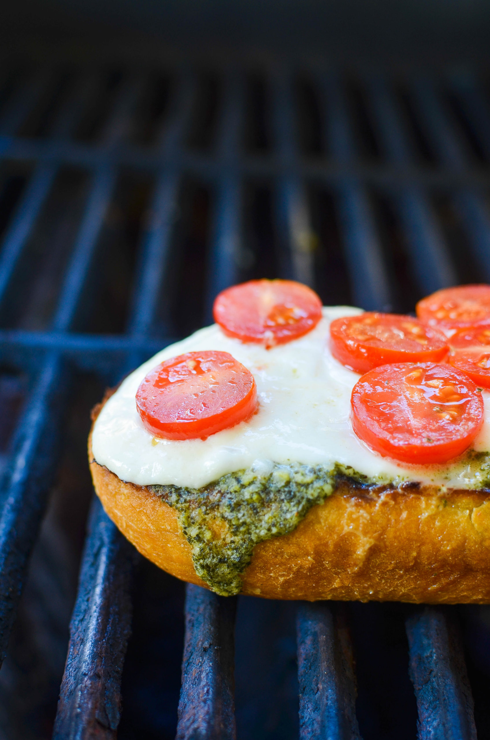 Bread on a grill with pesto, burrata and tomatoes