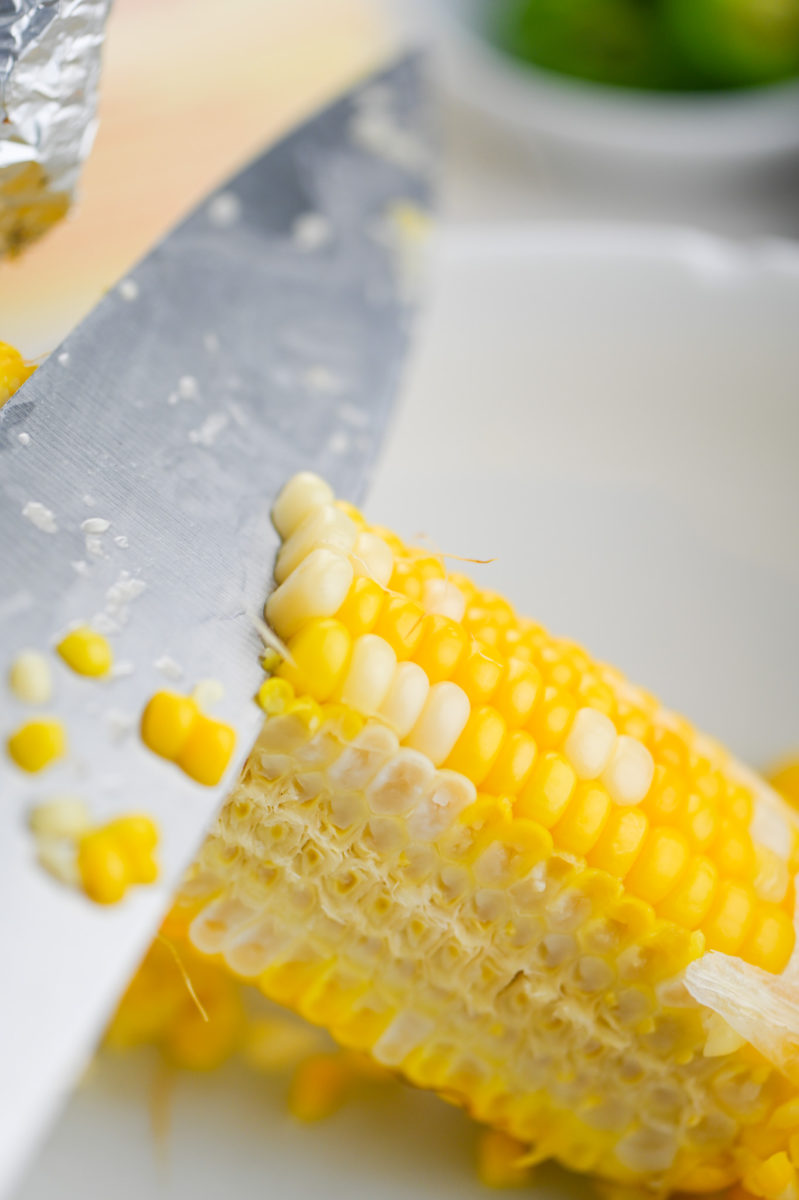 A knife removing corn kernels from the cob. 