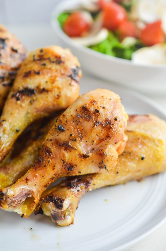 Grilled Garlic Chicken on white plate with a salad in the background.