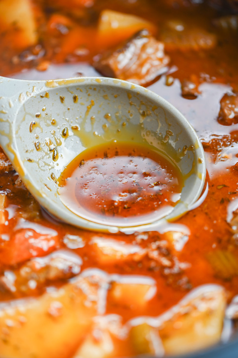 Spooning fat from top of beef stew.