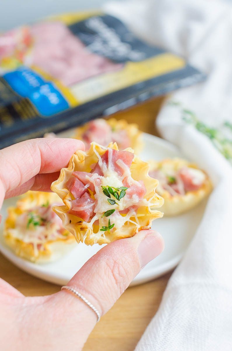 Hand holding ham and gruyere bites.