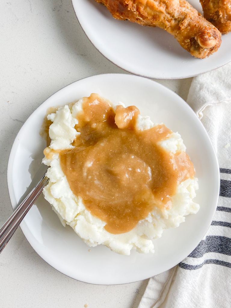 Overhead photo of mashed potatoes and gravy on a white plate. 